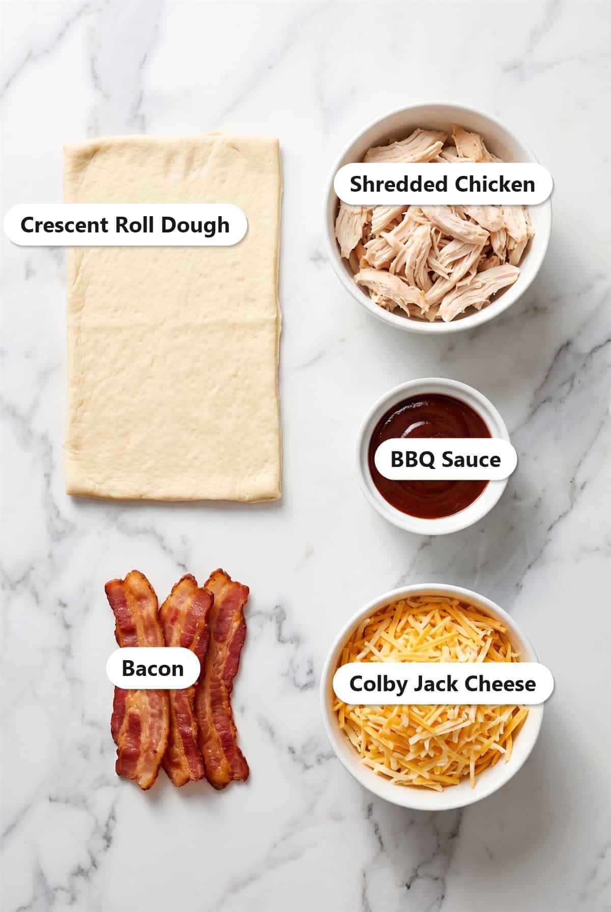 Ingredients to make Monterey chicken roll ups including crescent roll dough, shredded chicken, BBQ sauce, bacon, and colby jack cheese.