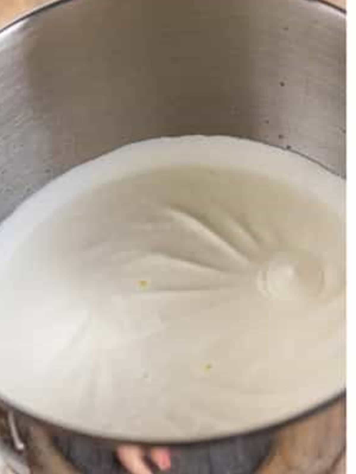 Heavy cream whipped to soft peaks in a stand mixer bowl.