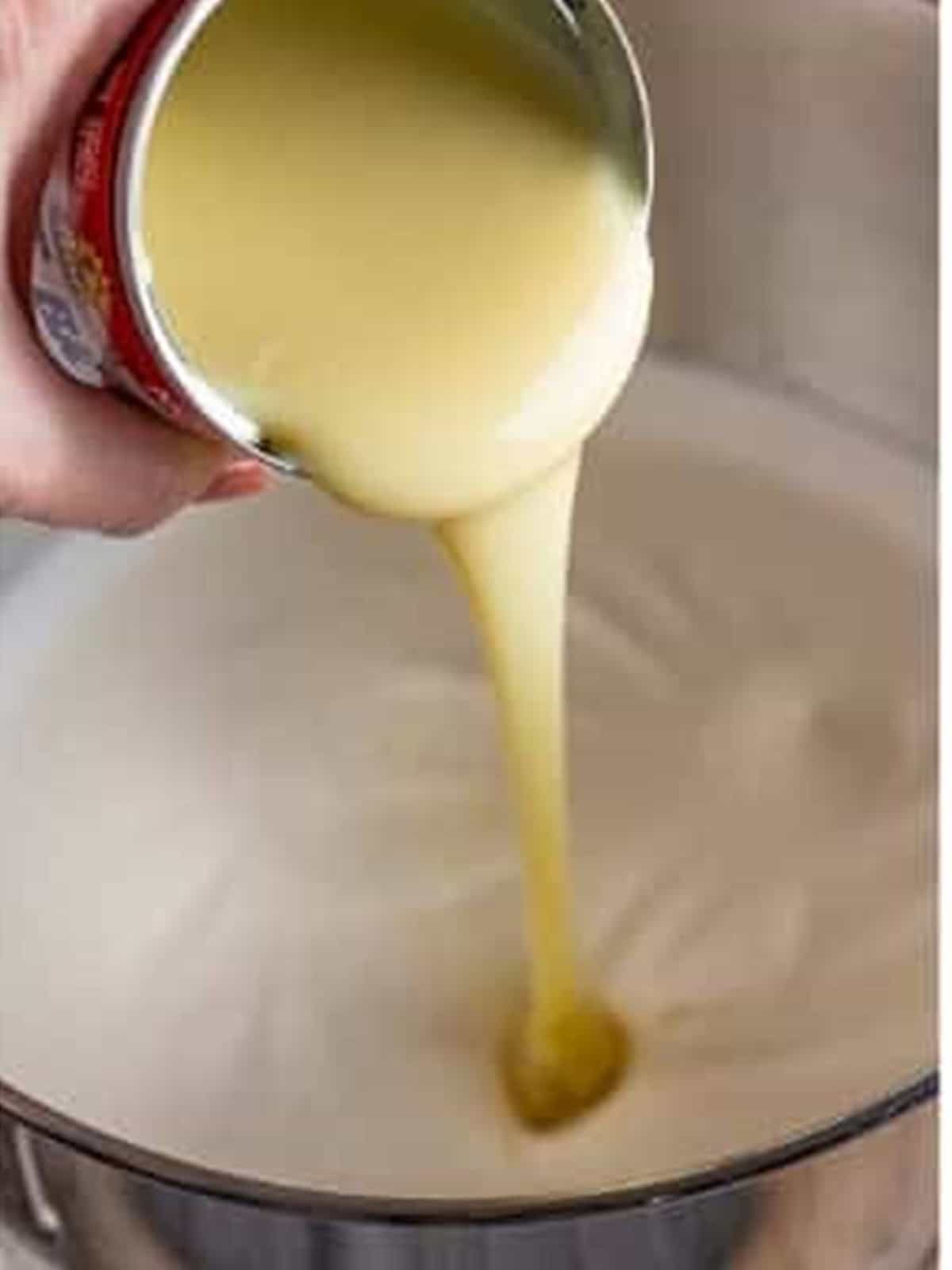 Sweetened condensed milk being poured into the whipped cream.