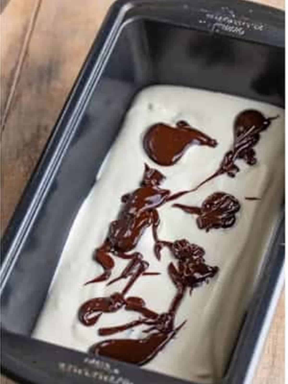 Hot fudge drizzled over the ice cream base in a loaf pan.