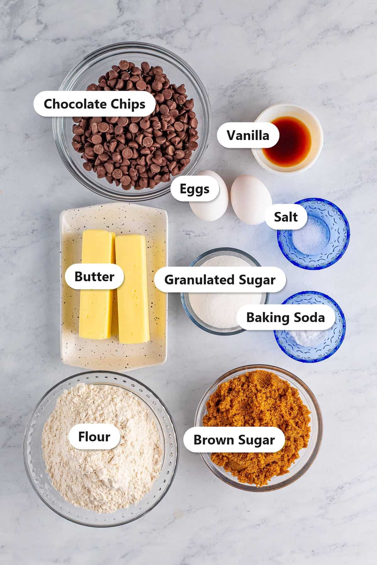 Labeled ingredients for Mrs Fields chocolate chip cookies including flour, butter, brown and granulated sugar, eggs, vanilla, and chocolate chips.
