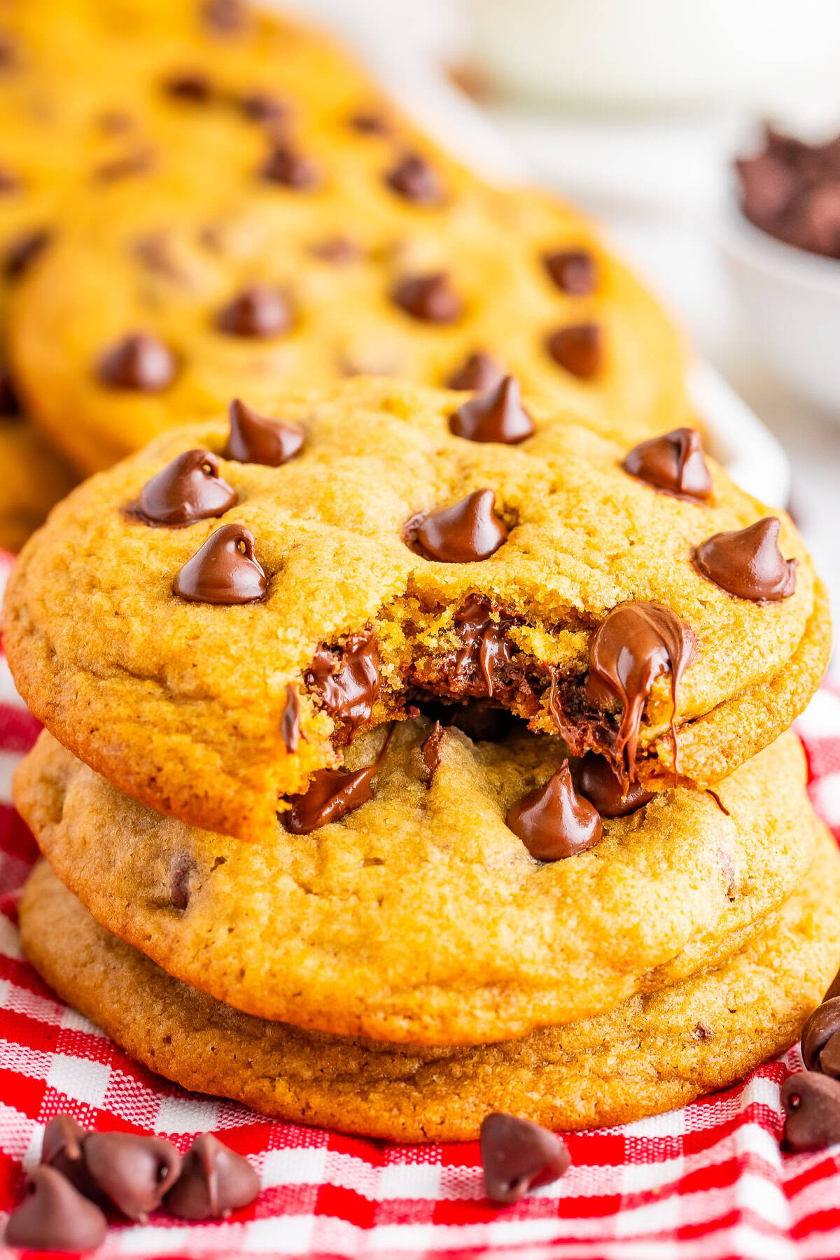 A gooey copycat Mrs Fields chocolate chip cookie with melty chocolate chips stacked on more cookies.