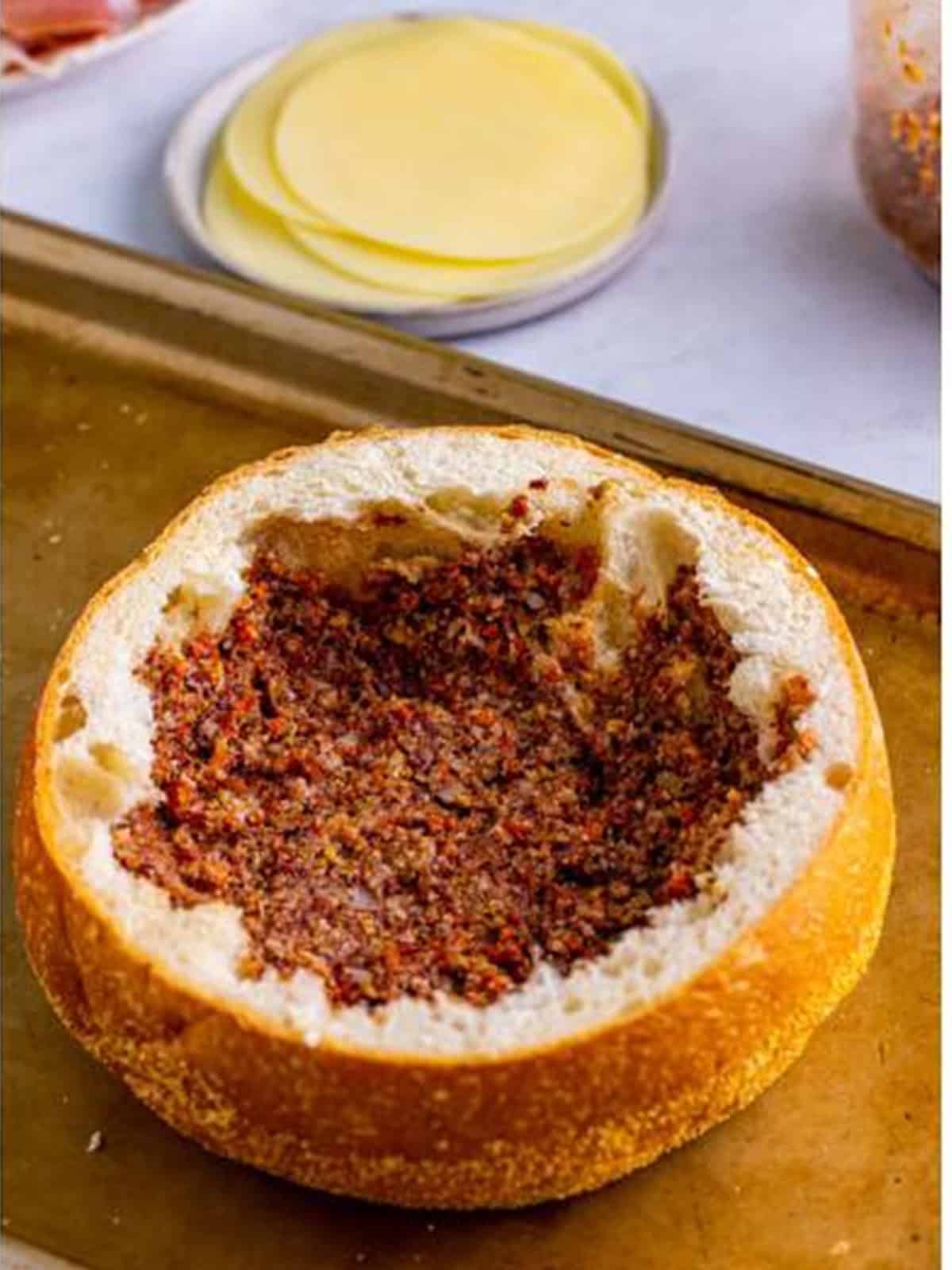 Olive spread spread evenly inside the hollowed round bread.