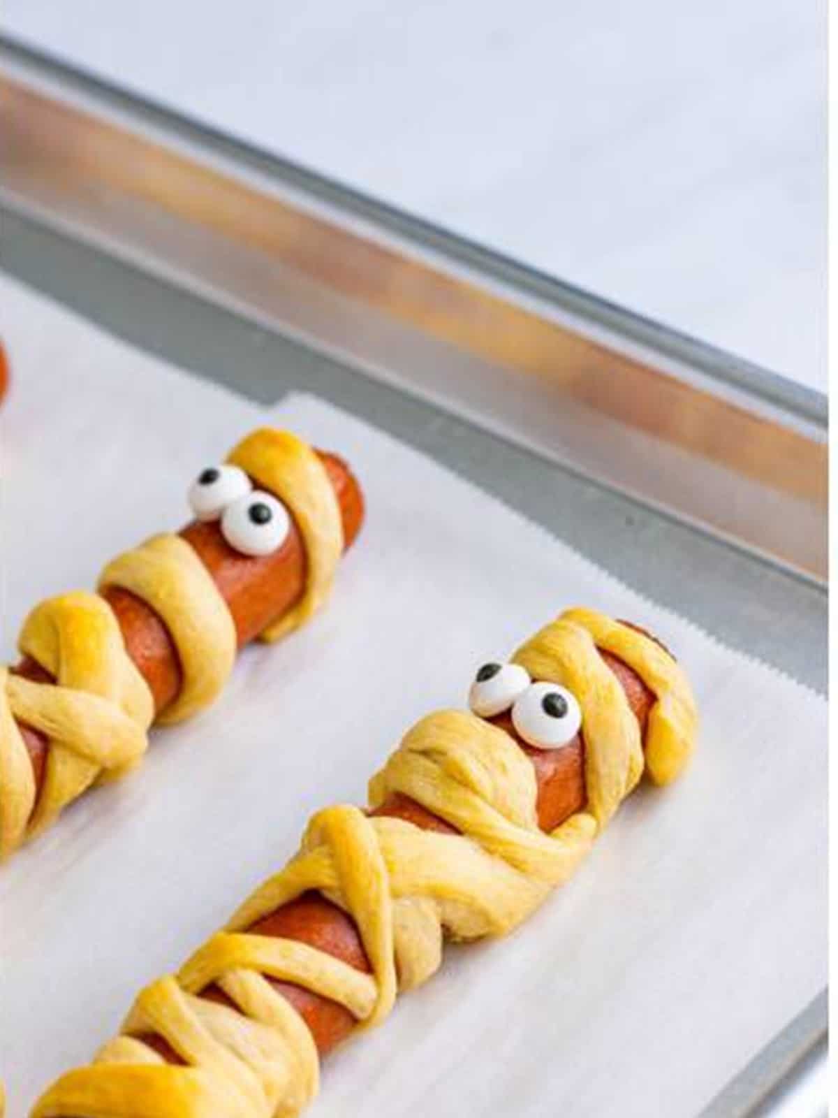 Candy googly eyes added to baked mummy dogs with a dab of ketchup.