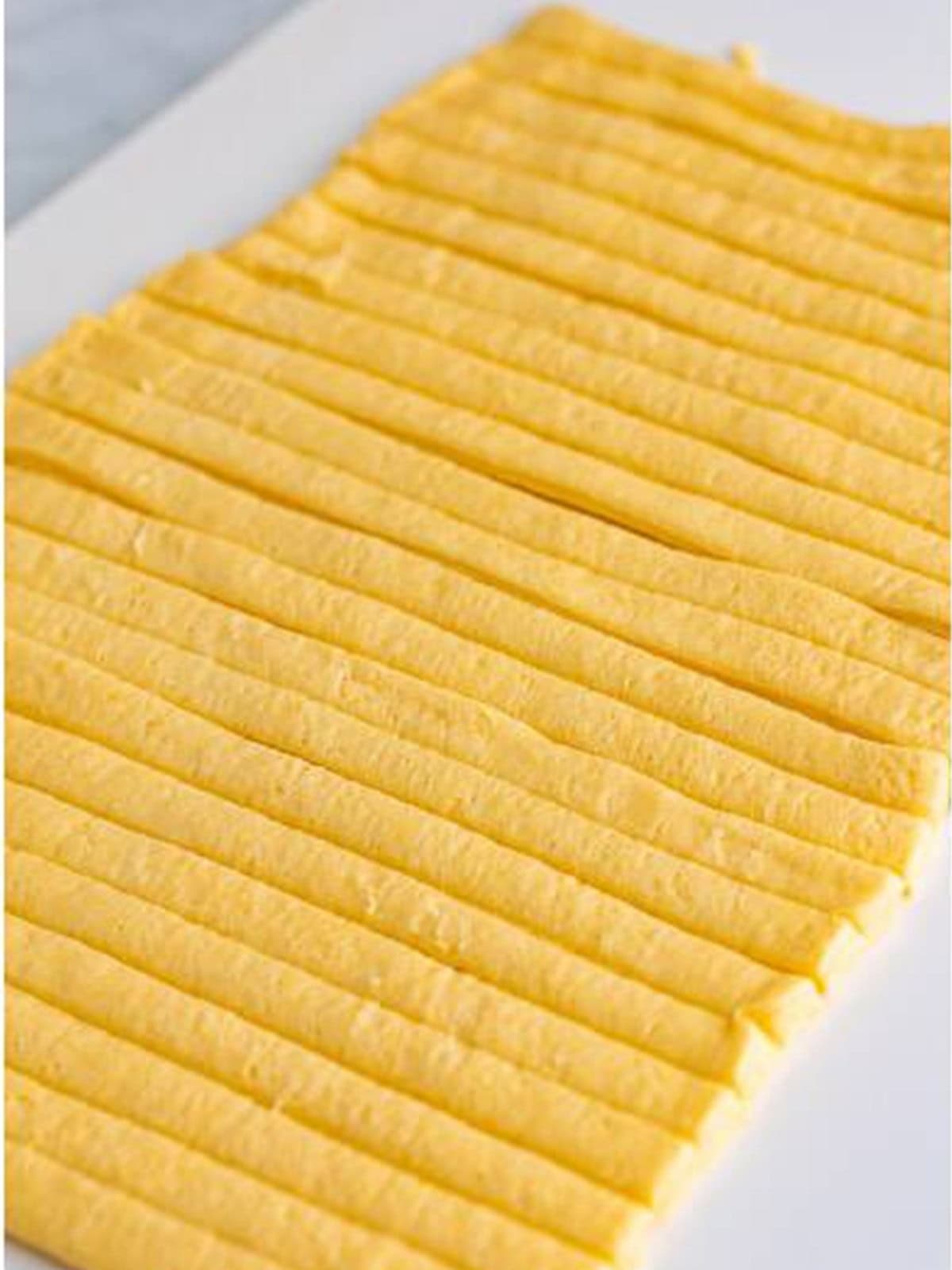Crescent dough sheet cut into thin strips for wrapping mummy dogs.