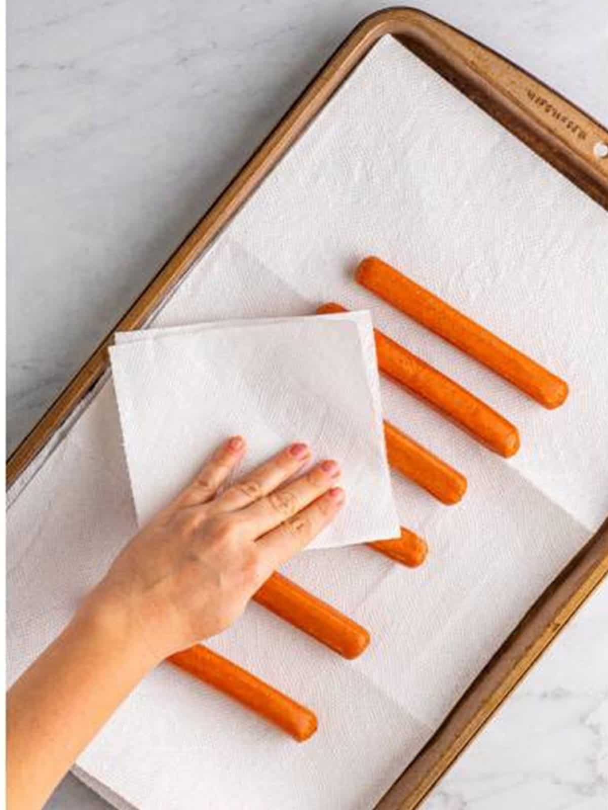 Hot dogs patted dry on a parchment lined sheet pan for mummy dogs.