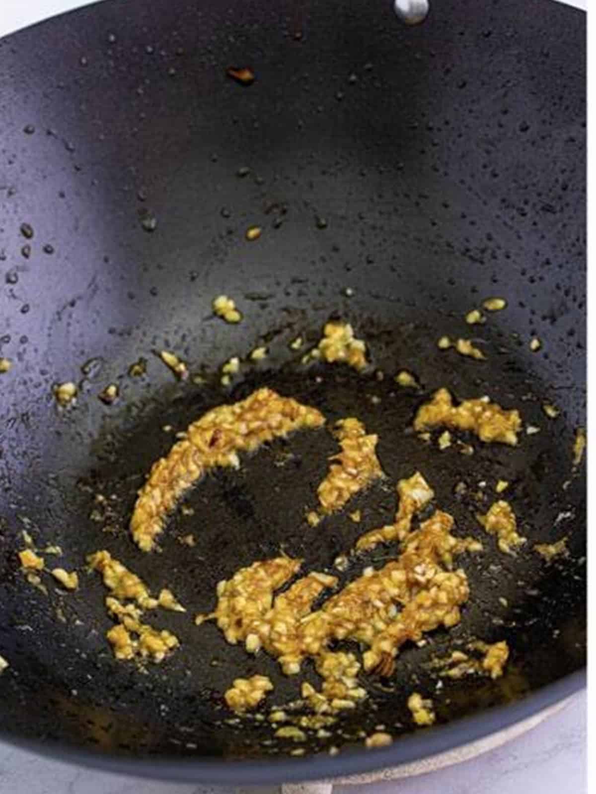 Minced ginger and garlic cooking until fragrant in a hot wok.