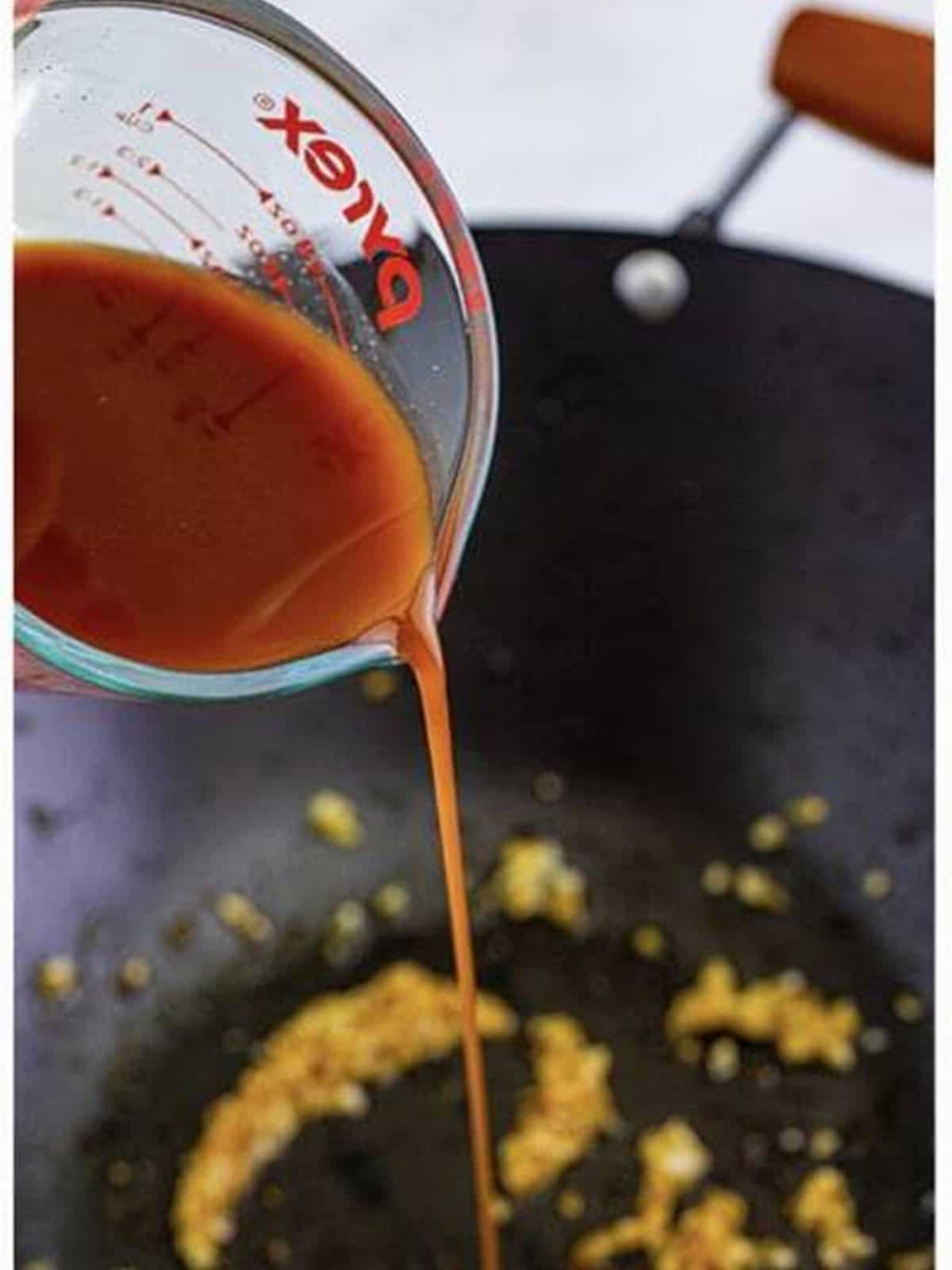 Brown sauce being poured into the wok for Panda Express mushroom chicken.