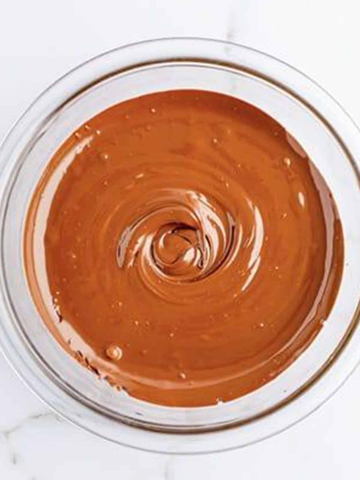 Melted chocolate in a glass bowl for Nestle crunch bars.