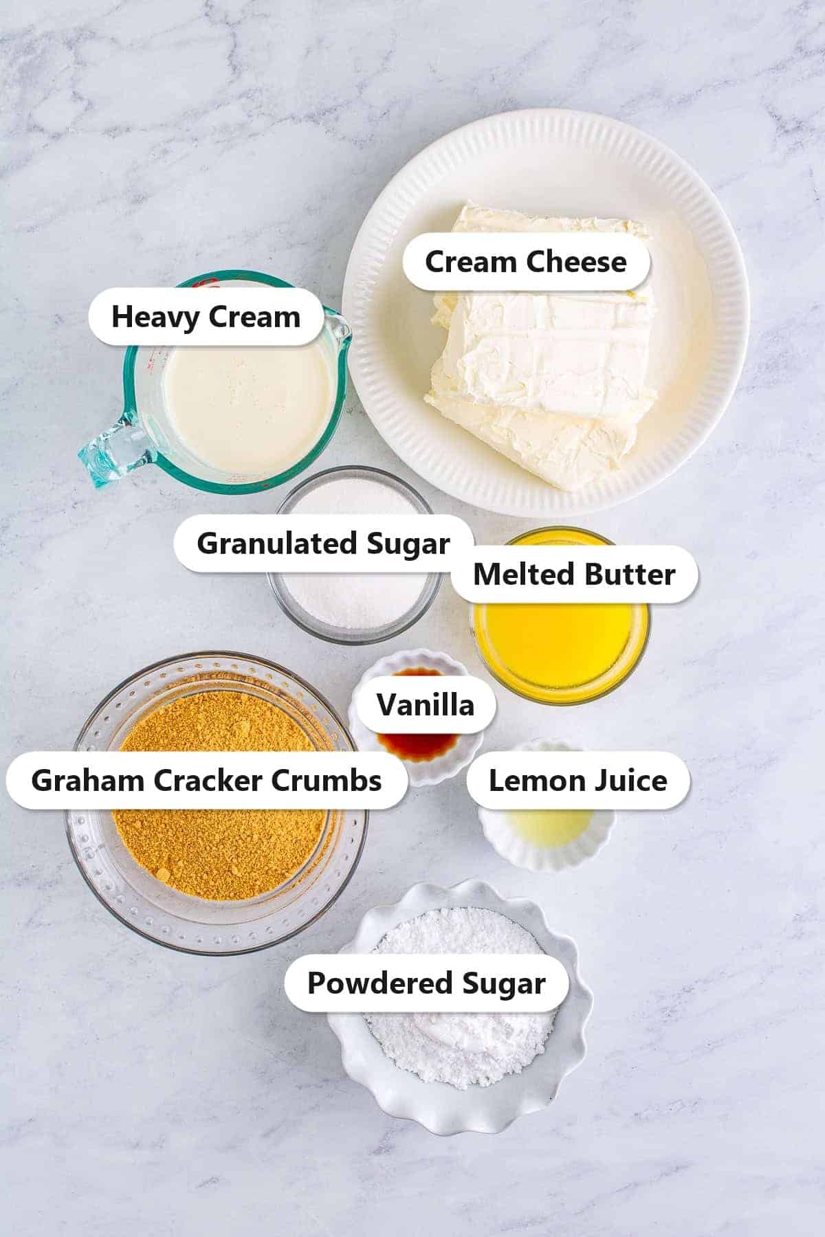 Labeled no bake cheesecake recipe ingredients including cream cheese, graham cracker crumbs, heavy cream, butter, and sugar.