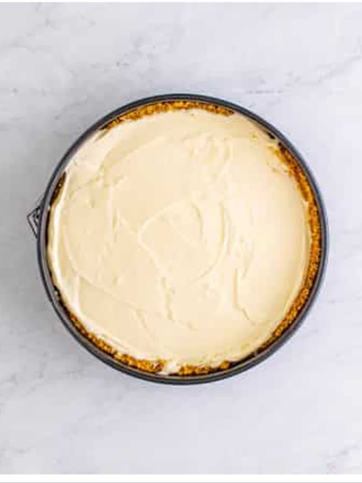 Spreading the filling into the crust for no bake cheesecake recipe.