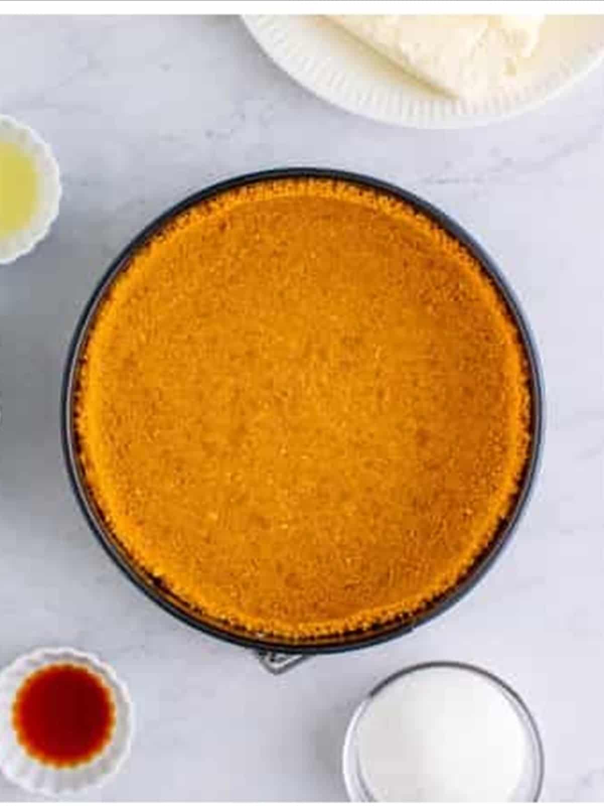Pressing the graham cracker crust into a springform pan for no bake cheesecake recipe.