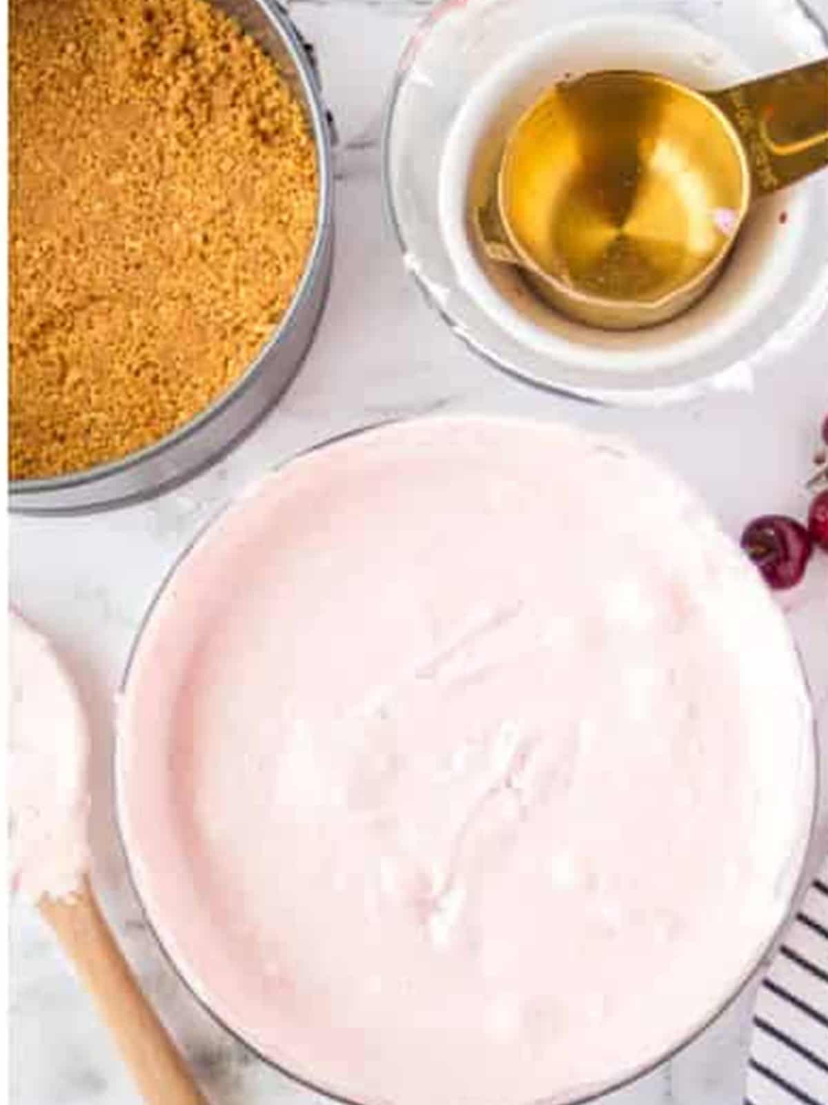 Pink cherry cheesecake filling poured into the graham cracker crust.