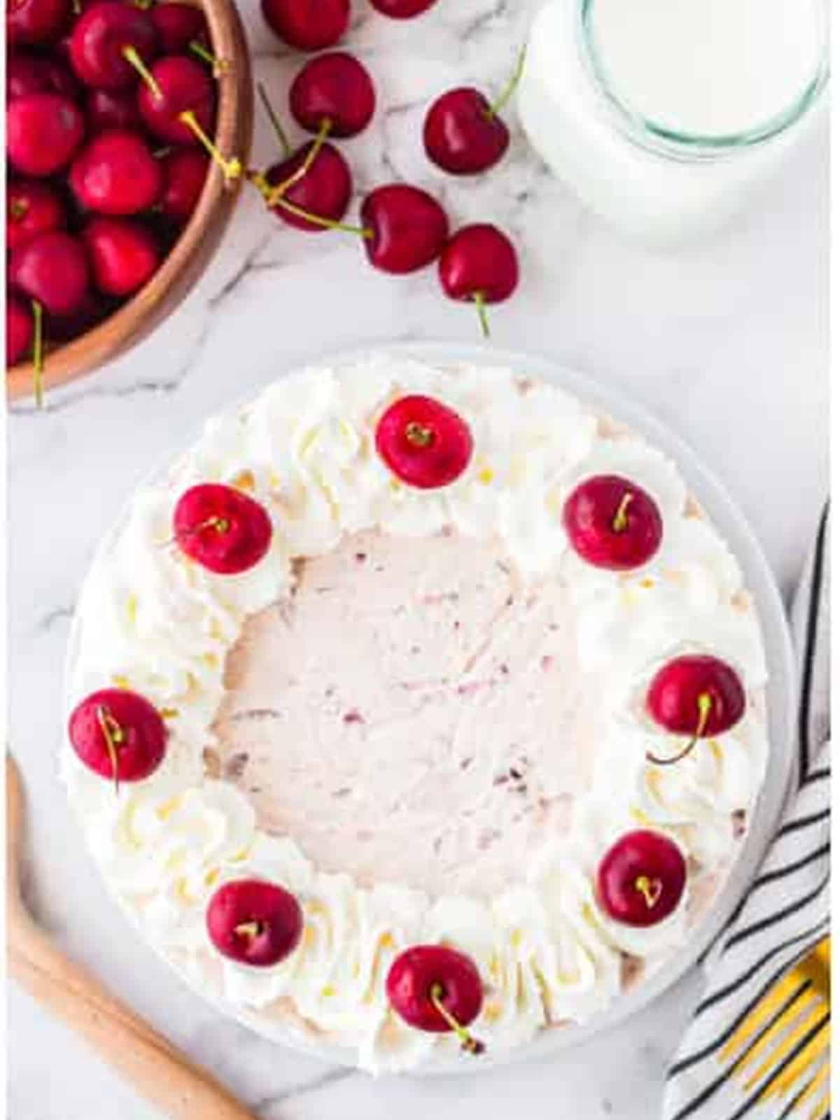 Finished no bake cherry cheesecake topped with whipped cream and fresh cherries.