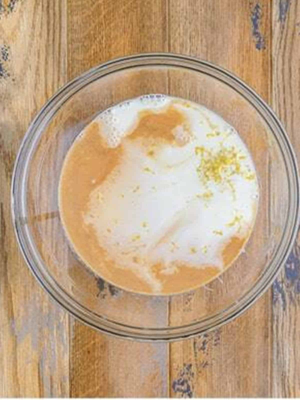 Condensed milk, milk, vanilla, and lemon zest in a glass bowl.
