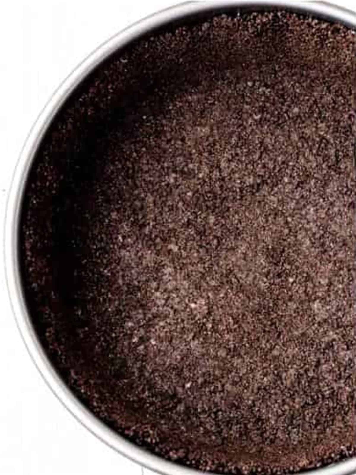Oreo cookie crust pressed into a springform pan for no bake Oreo cheesecake.