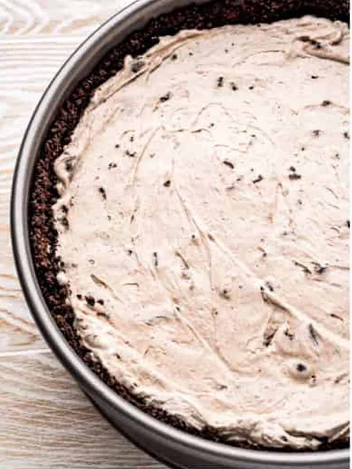 Cookies and cream filling spread into the Oreo crust for no bake Oreo cheesecake.