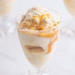 A parfait glass of no churn caramel ice cream drizzled with caramel sauce.