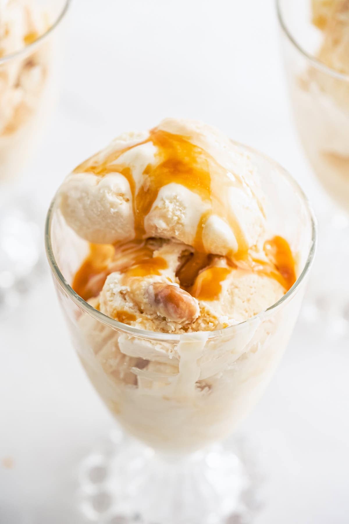 A glass of caramel ice cream topped with a swirl of caramel sauce.