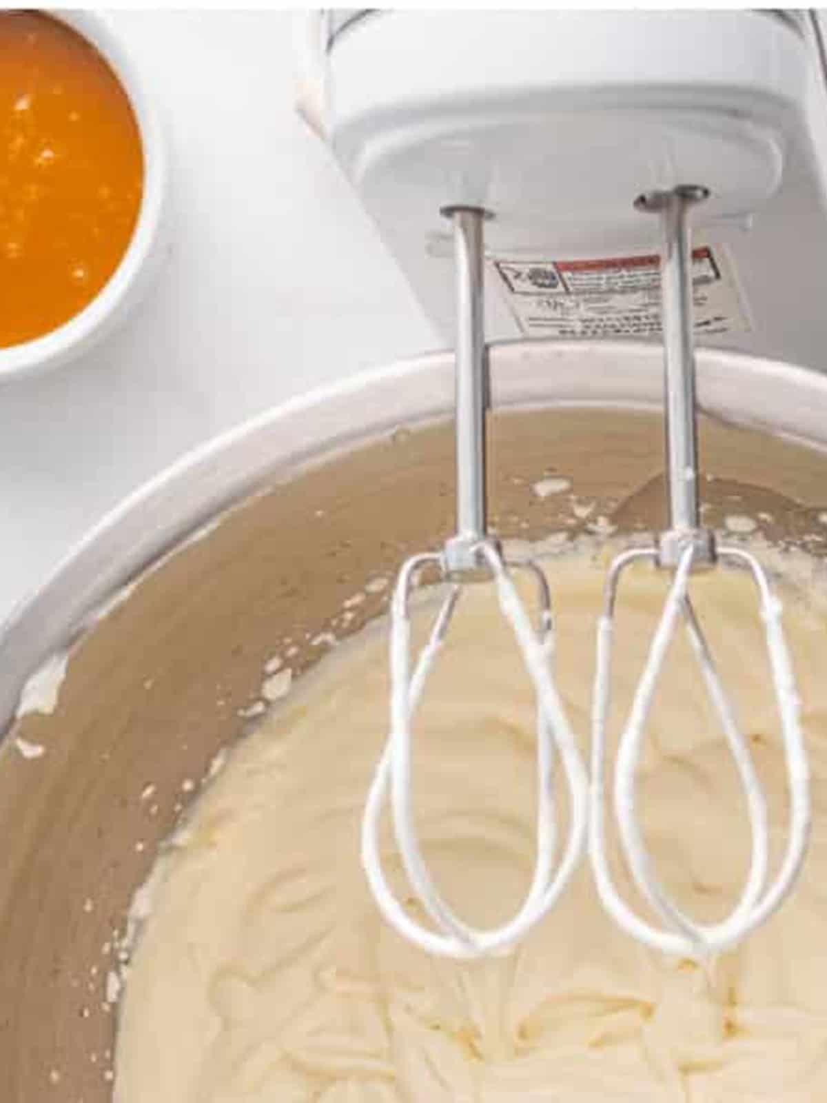 Heavy cream being whipped to soft peaks with a hand mixer.