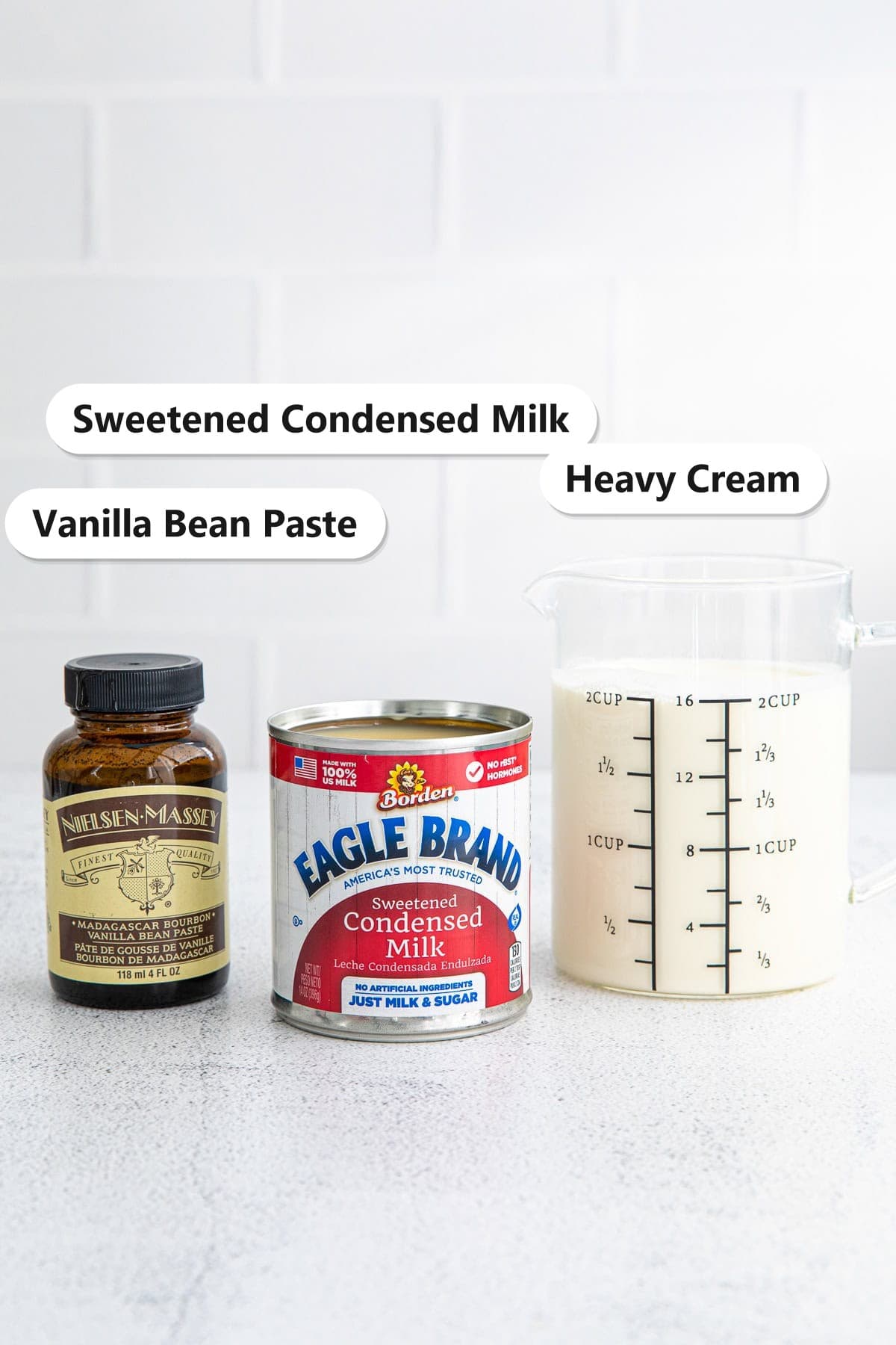 Labeled ingredients for no churn vanilla ice cream including heavy cream, sweetened condensed milk, and vanilla bean paste.