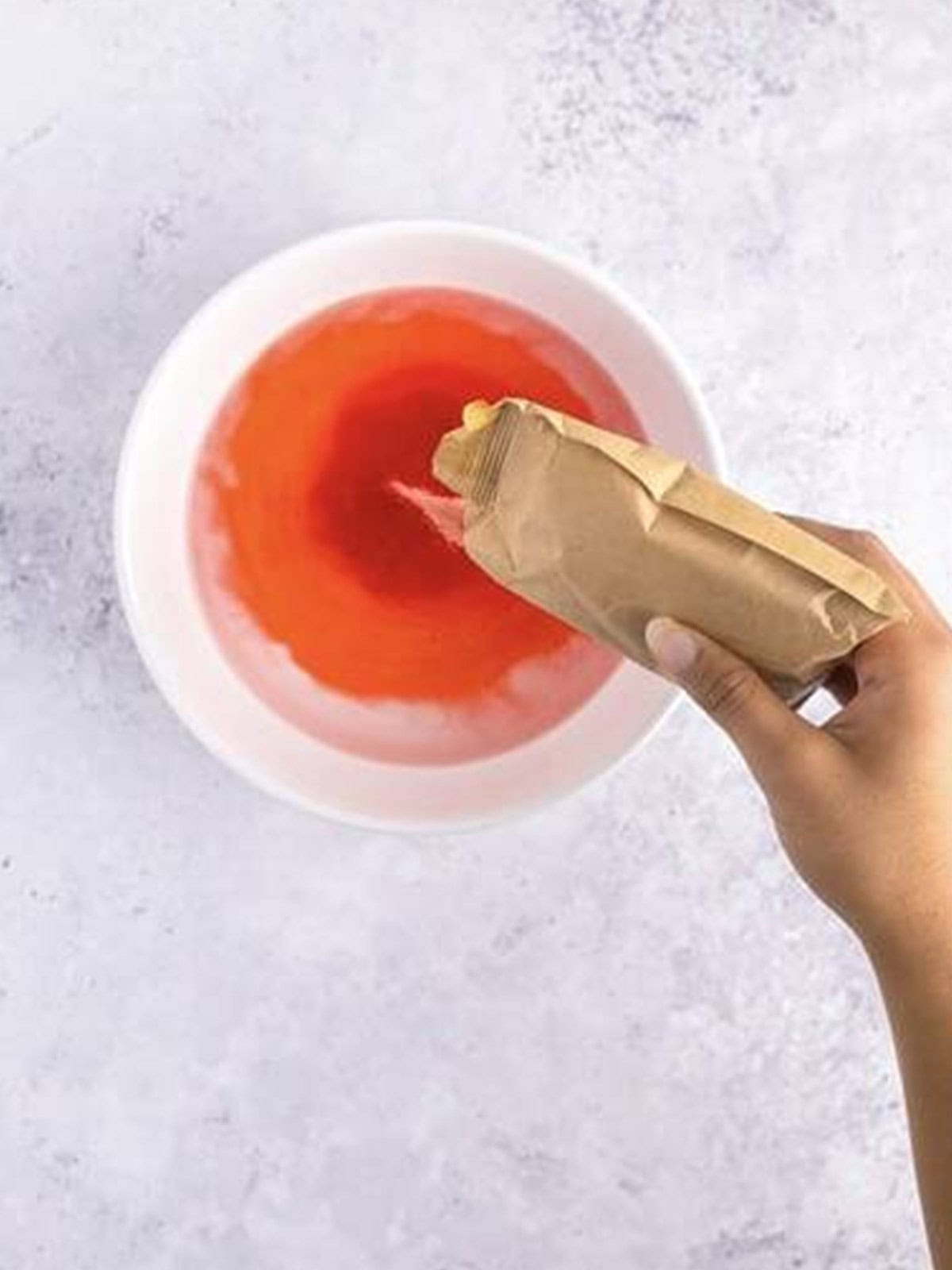 Jell-O powder added to a bowl of boiling water.