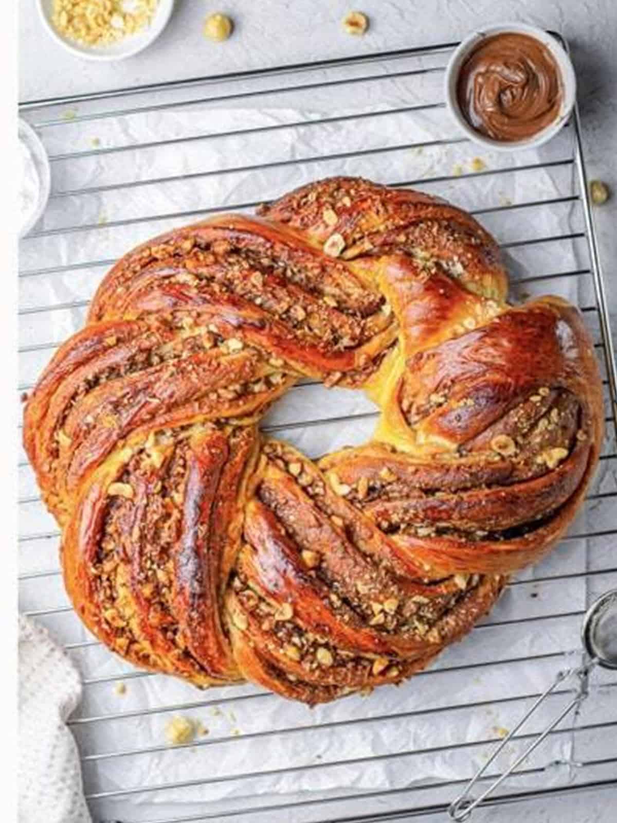 Golden baked Nutella braided bread wreath being brushed with egg wash.