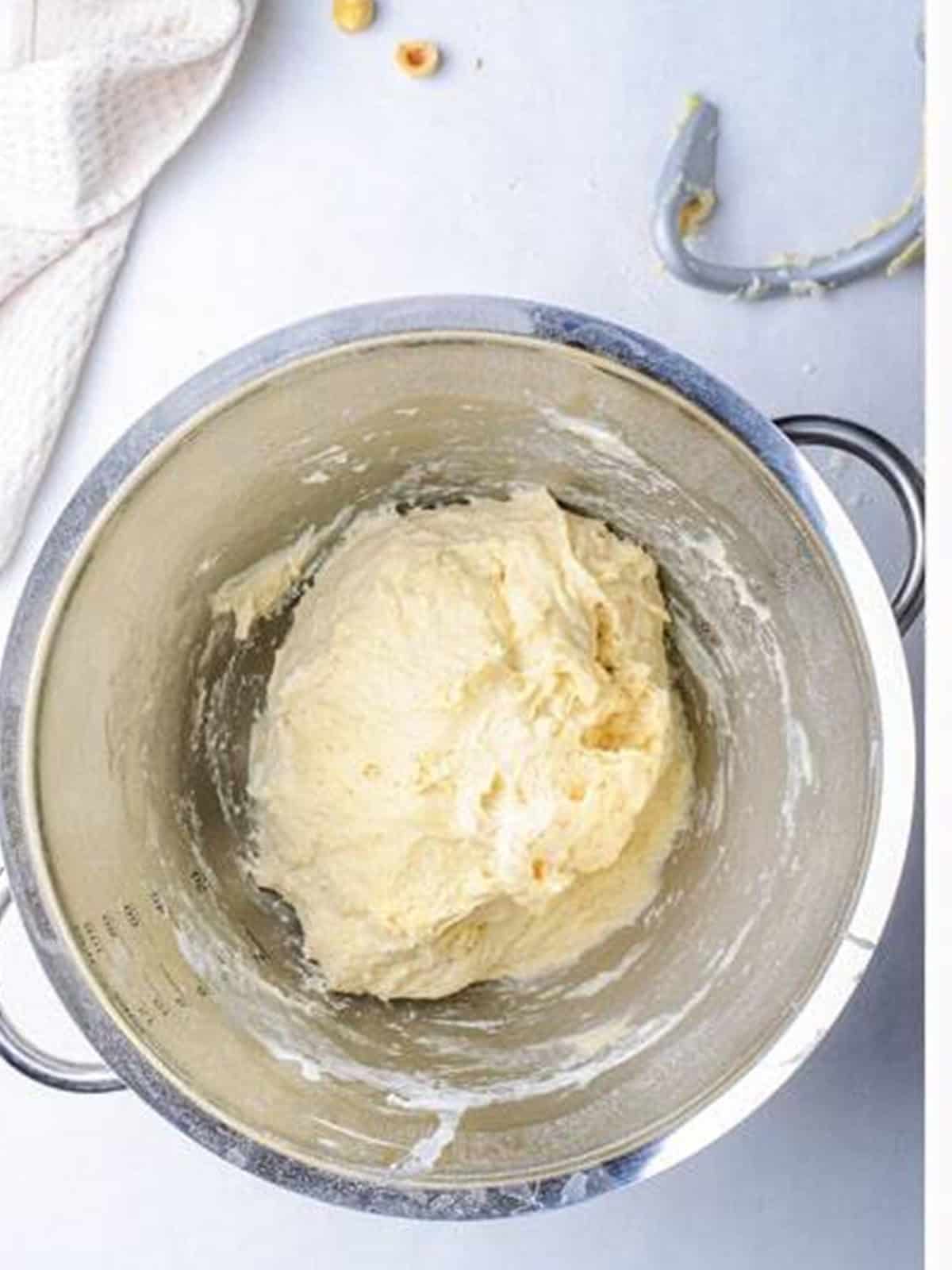 Smooth bread dough kneaded into a ball in a mixing bowl.