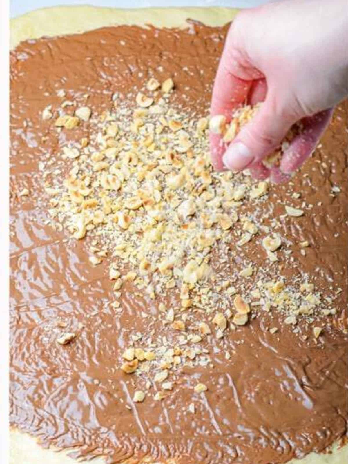 Nutella spread over rolled out dough and sprinkled with chopped hazelnuts.