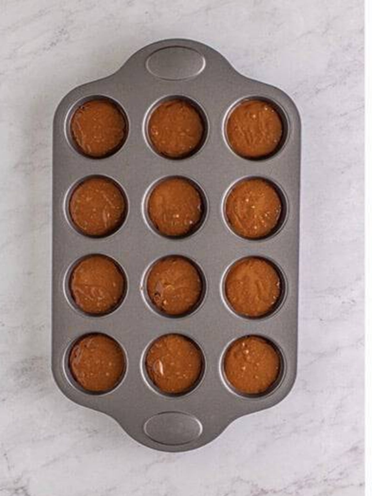 Chocolate batter added to the bottom of muffin cups for Nutella Muffins.