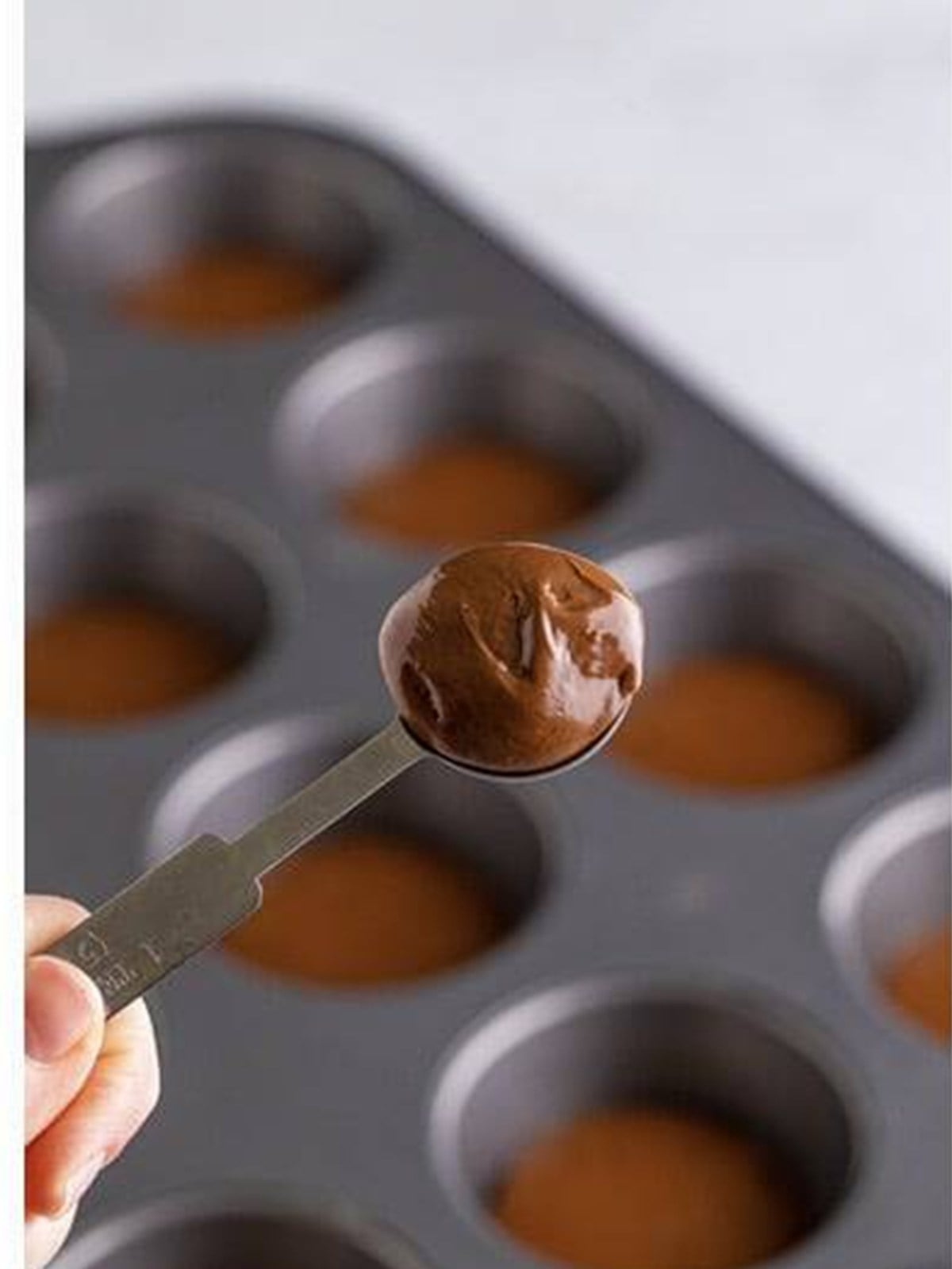 Adding a scoop of Nutella to the center of each muffin.