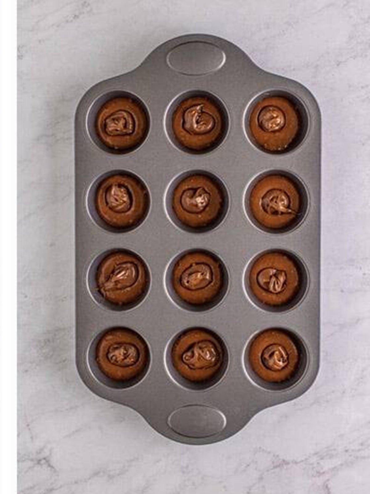 Covering the Nutella with more batter for stuffed Nutella Muffins.