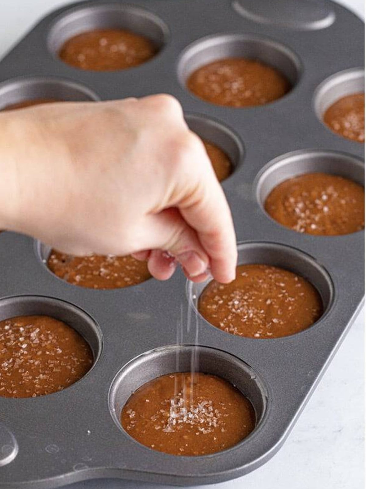 Sprinkling decorators sugar on top of the Nutella Muffins.