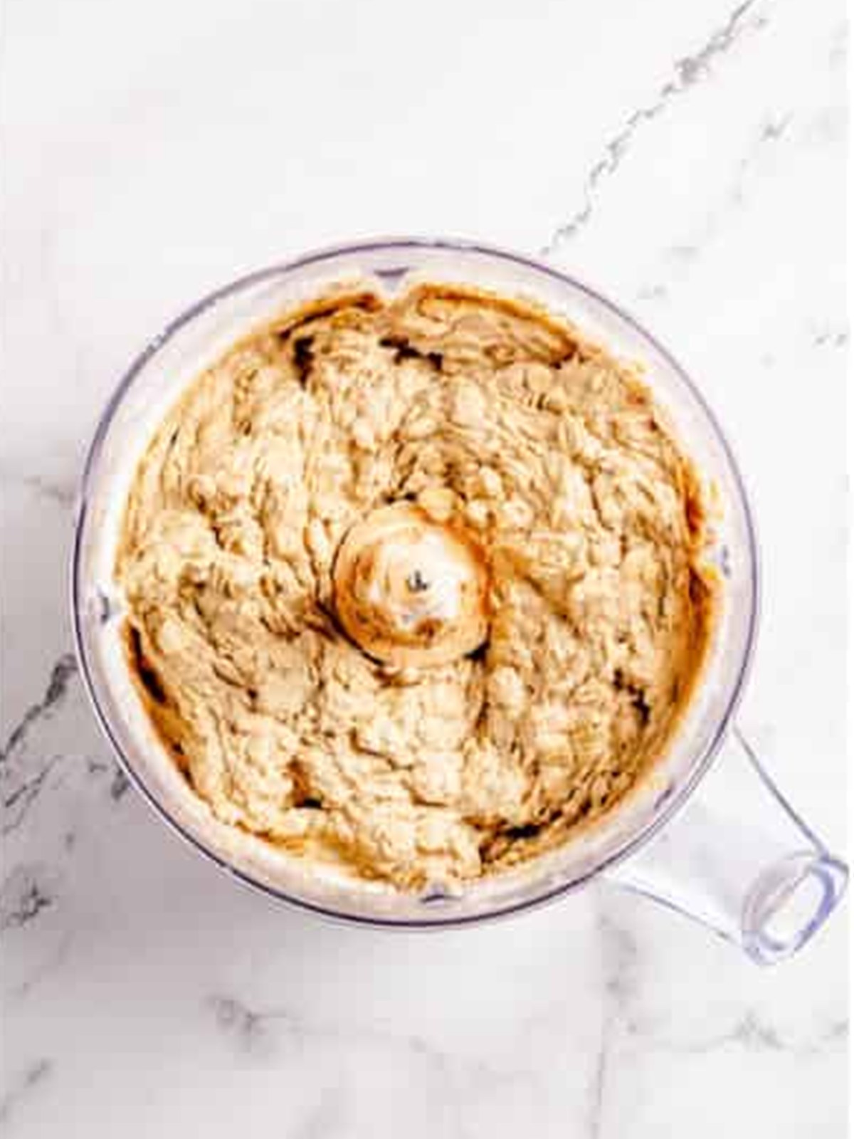 Oatmeal cookie dough mixed together in a stand mixer bowl.