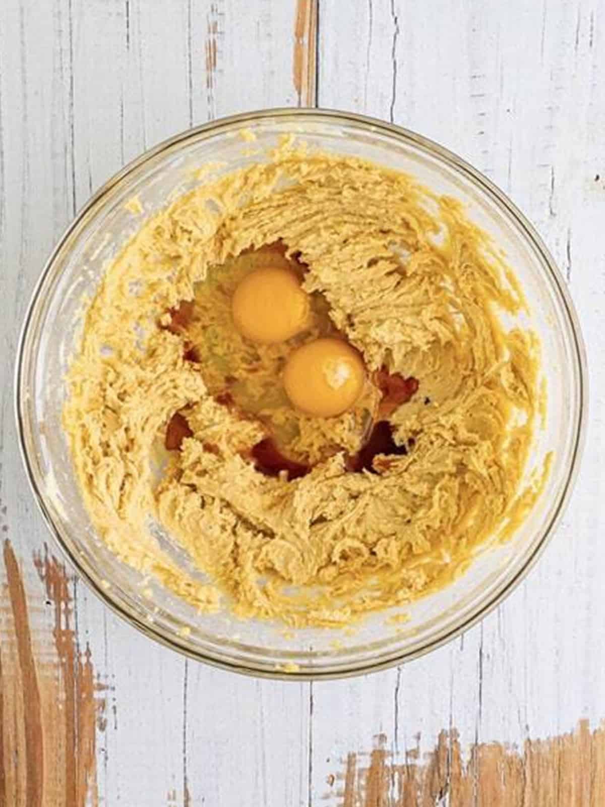 Adding eggs and vanilla to creamed butter and brown sugar.