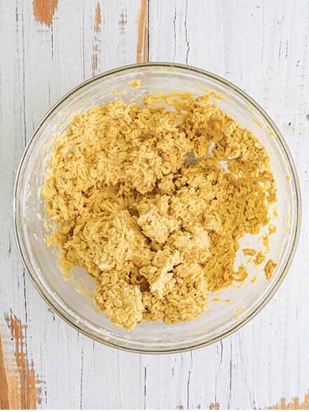 Mixing the dry ingredients into the wet to form a thick cookie bar dough.