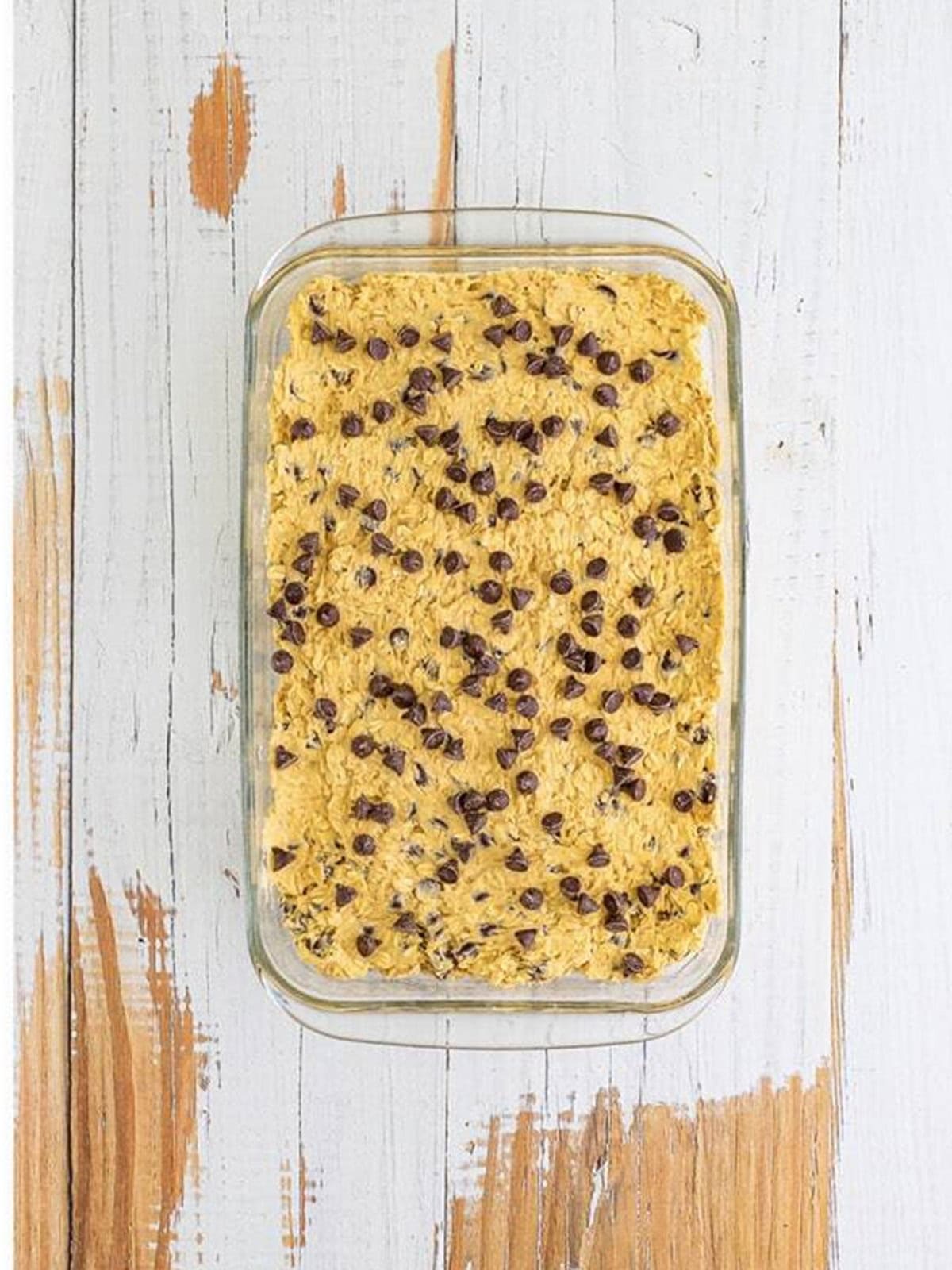 Cookie bar dough pressed into a baking dish and topped with extra chocolate chips.