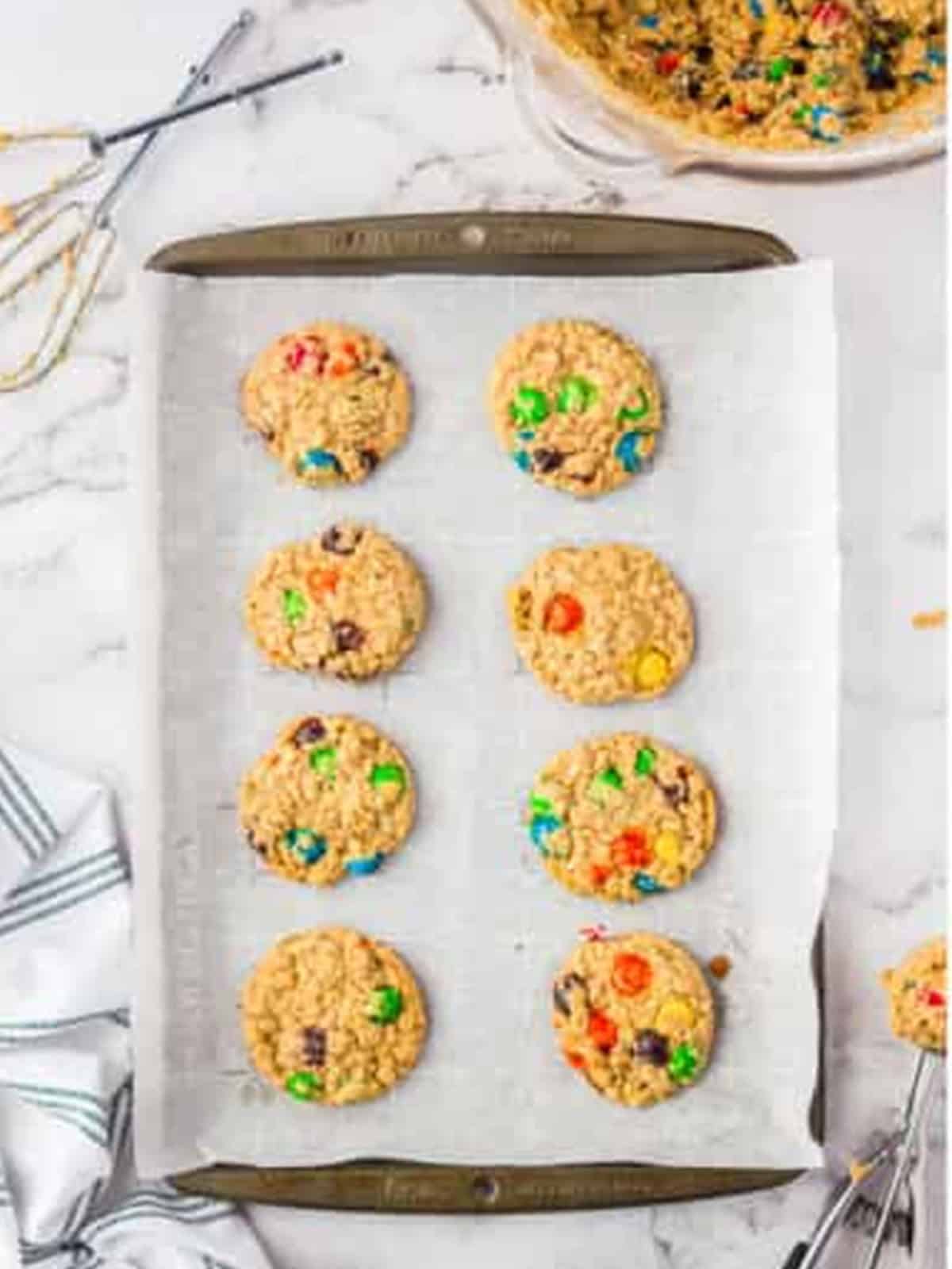 Baked oatmeal M&M cookies golden brown on the parchment-lined sheet tray.