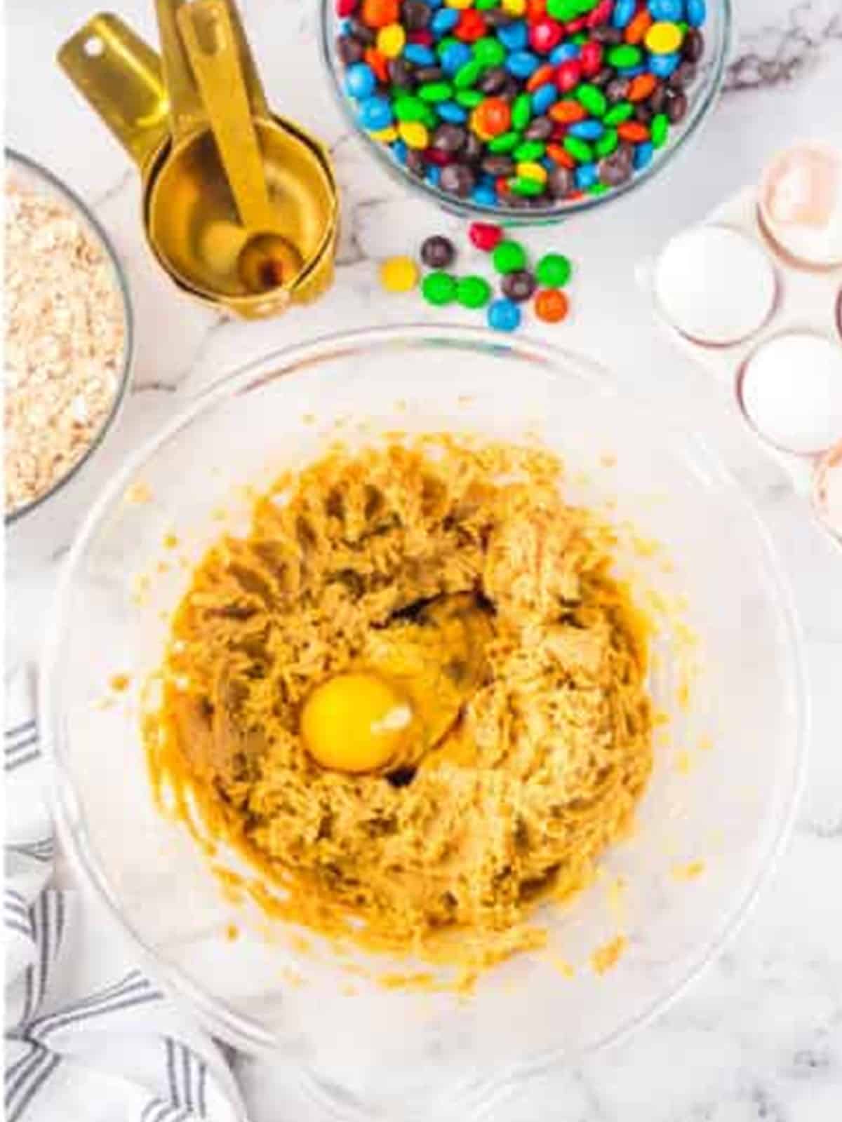 Butter and sugars creamed together with an egg added in a glass mixing bowl.