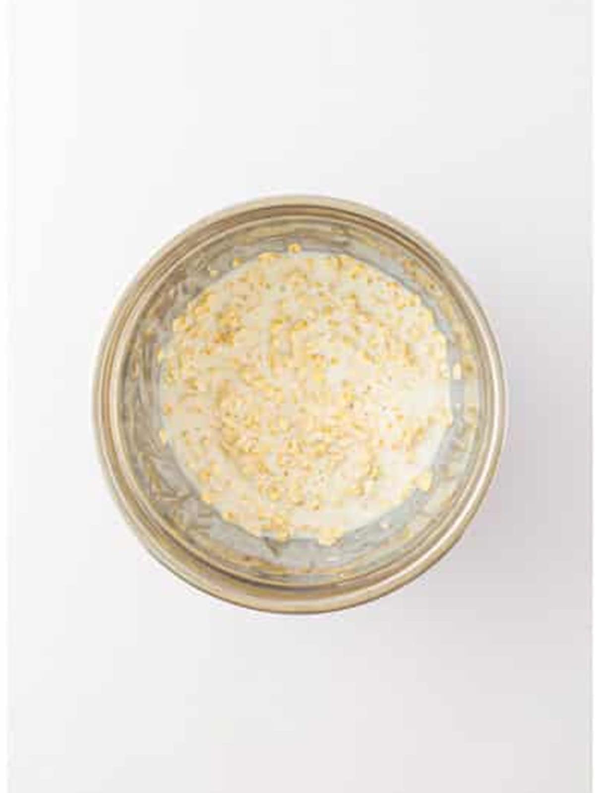 Old fashioned oats soaking in buttermilk in a glass bowl.