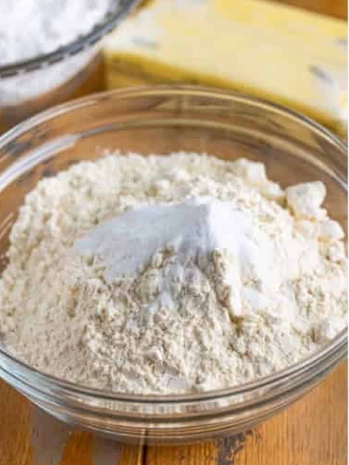 Flour and baking soda stirred together in a glass bowl for caramel cake.