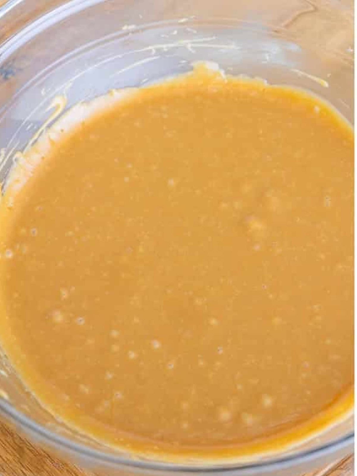 Smooth homemade caramel frosting in a glass bowl.