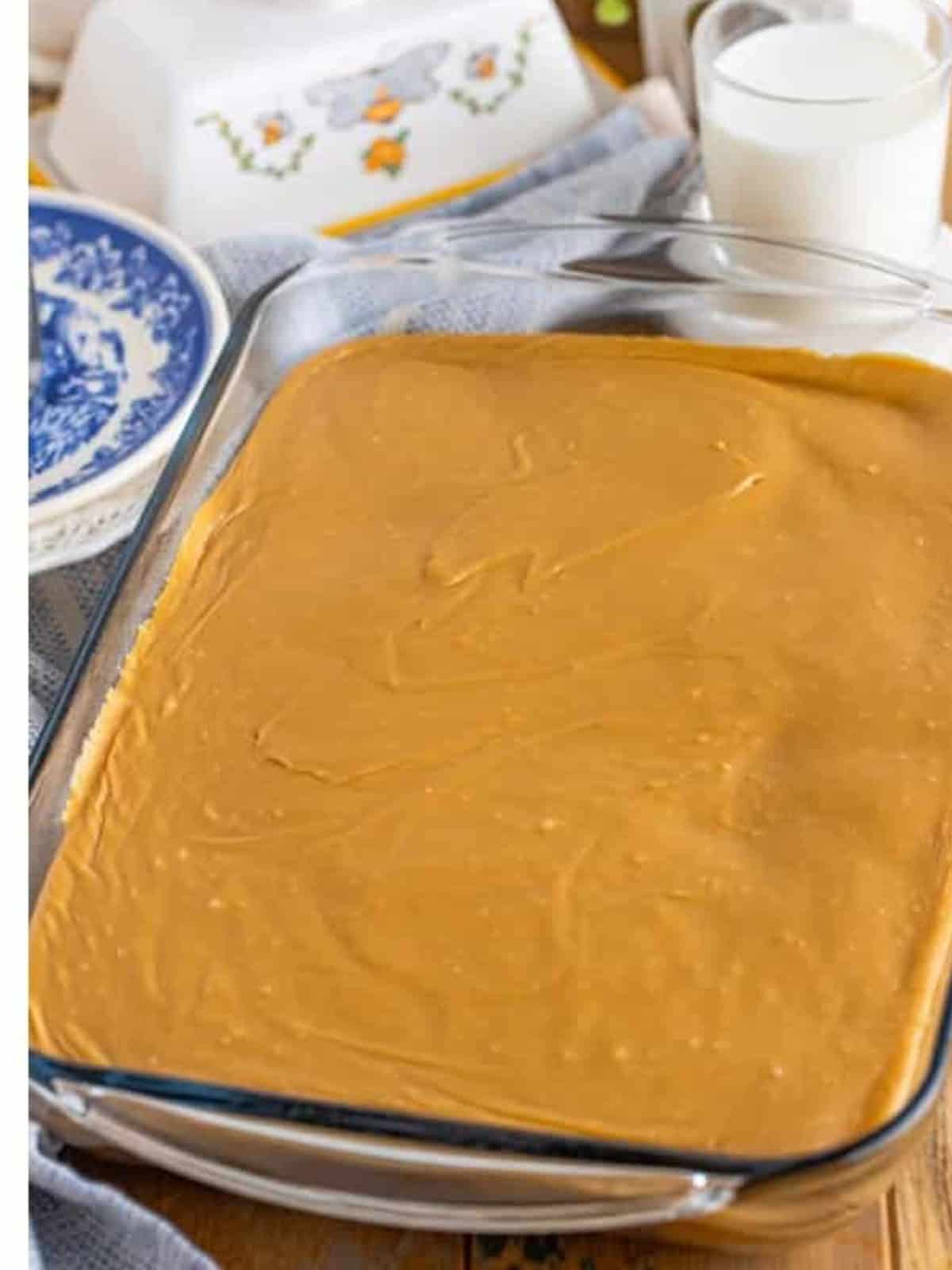 Caramel frosting spread over the cake in a baking dish.