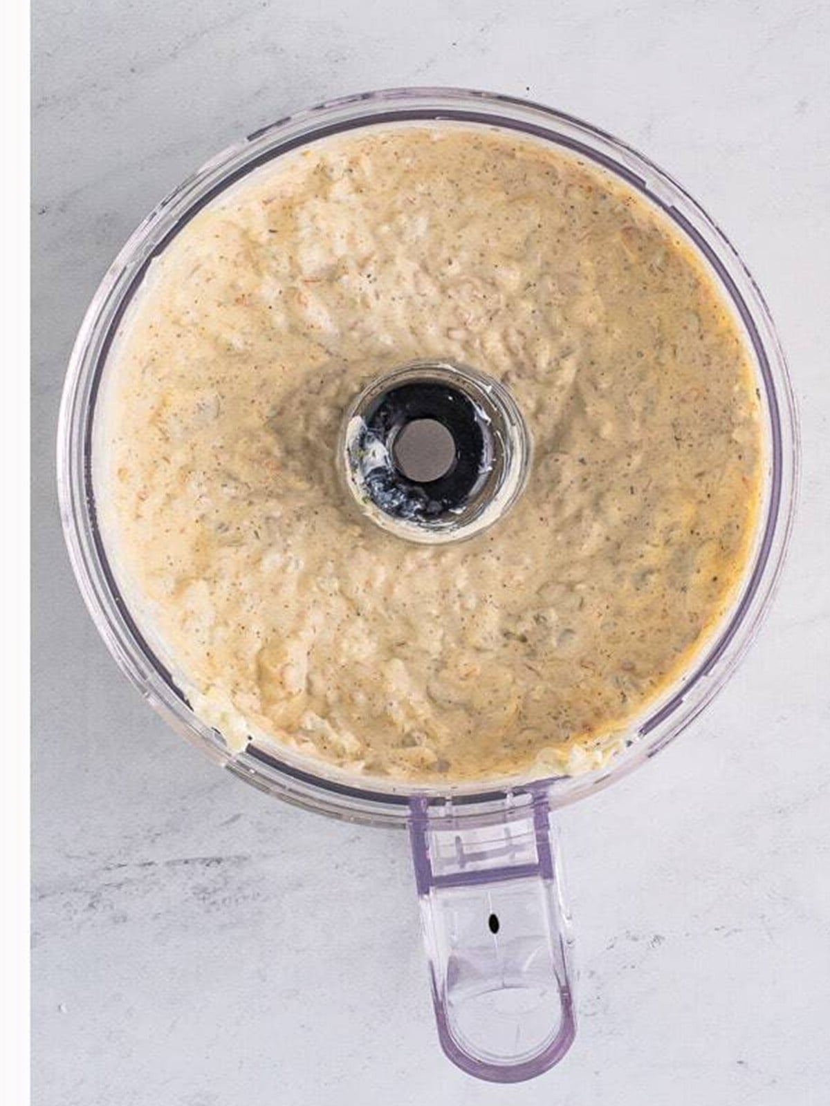 Blended creamy olive dip in a food processor.