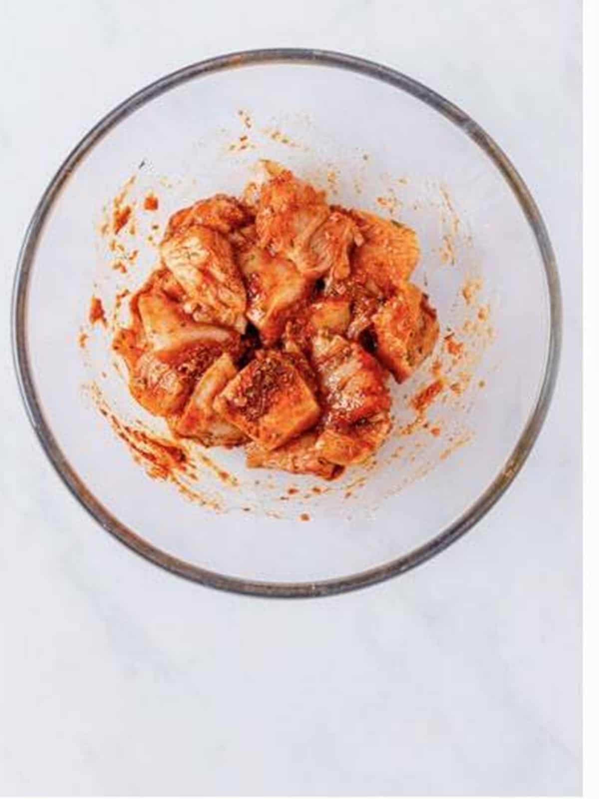 Bite-size chicken pieces tossed in red pesto and seasonings to marinate.