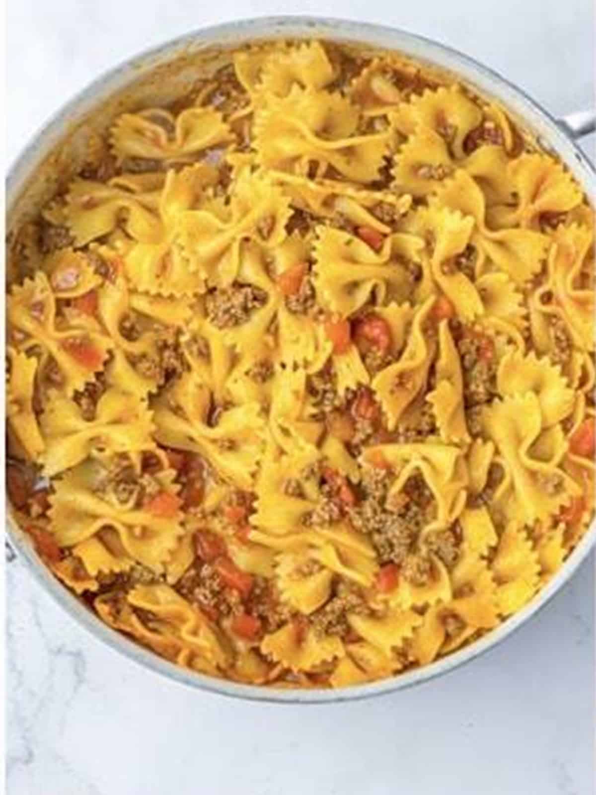 Cooked bowtie pasta simmered in tomato sauce for one pot lasagna.