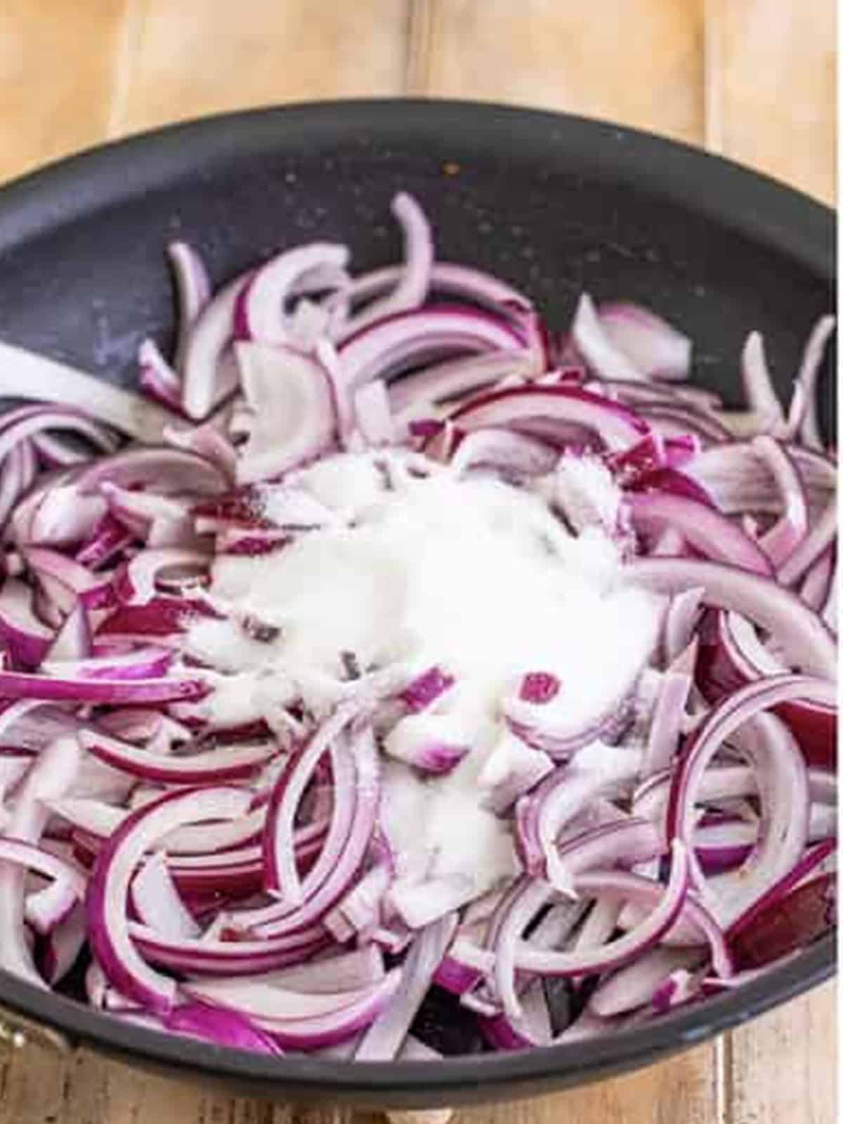Sliced red onions and sugar added to a pan with butter and bacon drippings.