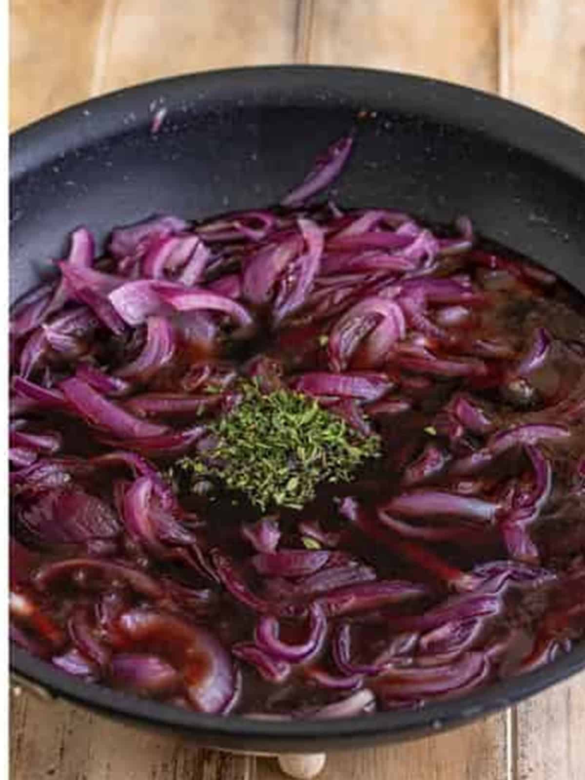 Adding red wine, balsamic vinegar, and thyme to the caramelized onions.