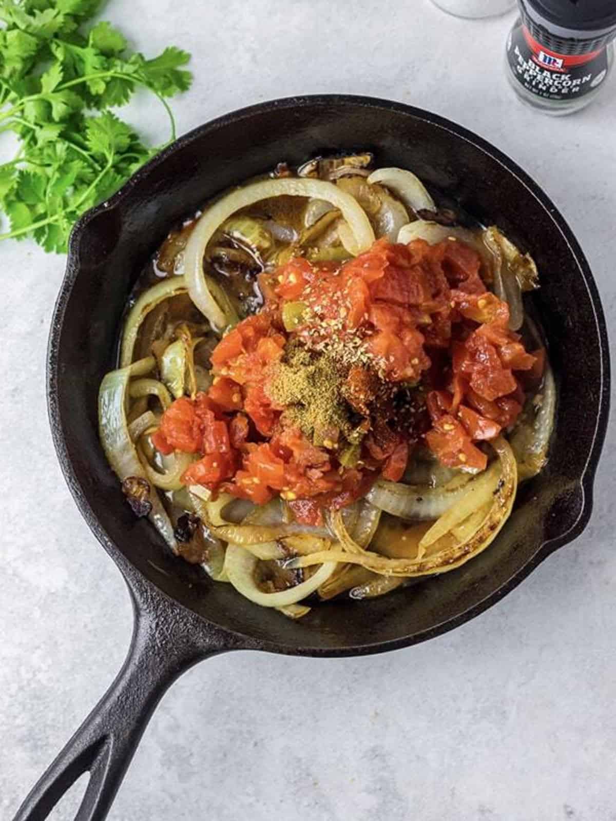 Adding Rotel diced tomatoes and spices to the cooked onions.