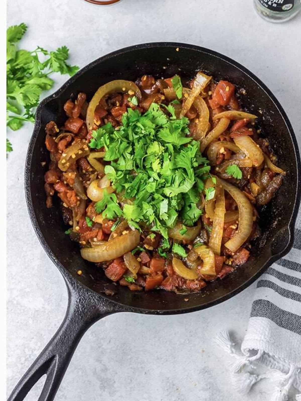 Finished chunky tomato onion relish simmered with cilantro in the skillet.
